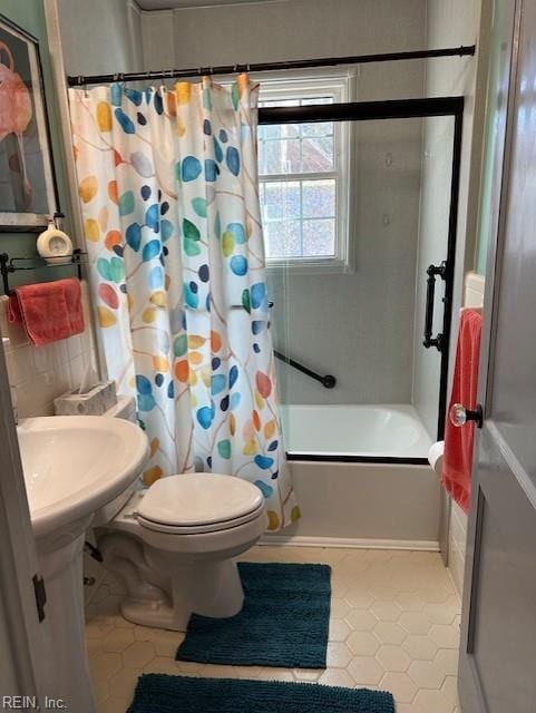 bathroom featuring toilet, tile patterned floors, and shower / bath combo with shower curtain