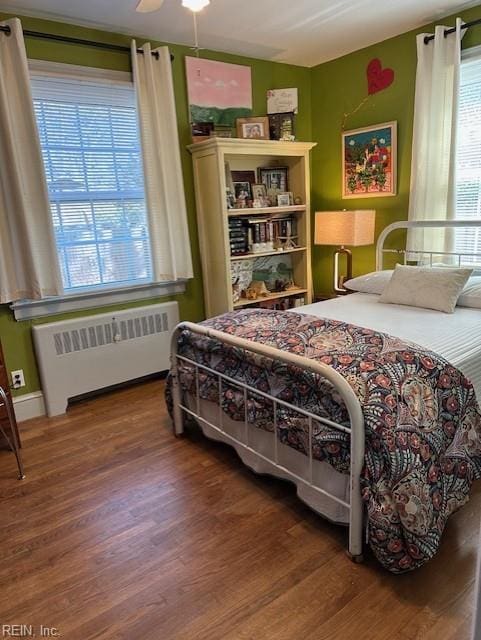 bedroom featuring hardwood / wood-style flooring, radiator heating unit, and ceiling fan