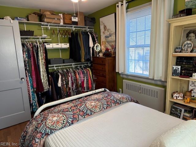 bedroom featuring radiator, hardwood / wood-style floors, and a closet