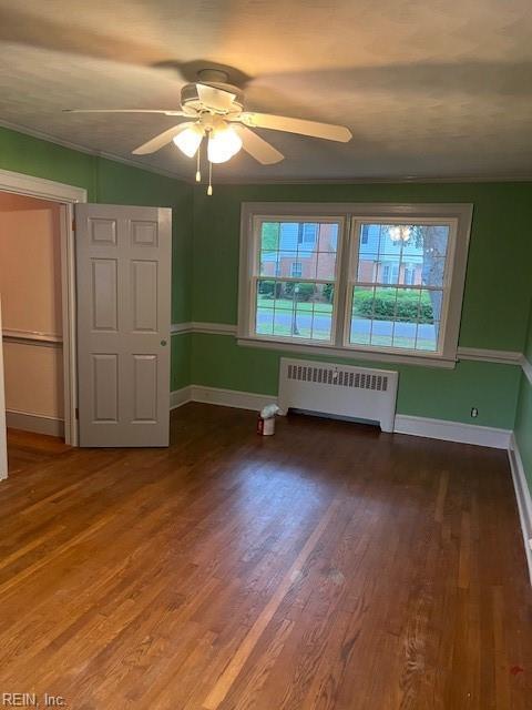 interior space with wood-type flooring, ornamental molding, radiator heating unit, and ceiling fan