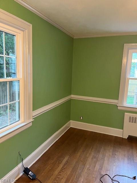 spare room featuring crown molding, radiator, and hardwood / wood-style floors