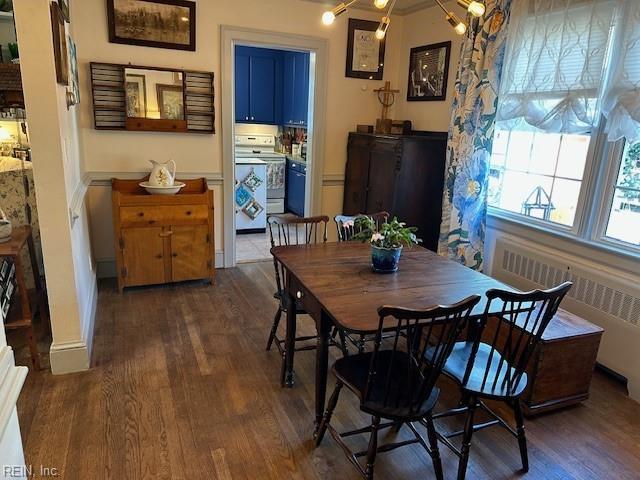 dining room with an inviting chandelier, dark hardwood / wood-style floors, and radiator