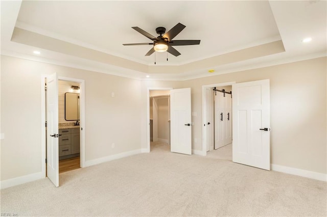 unfurnished bedroom with a spacious closet, light colored carpet, and a raised ceiling