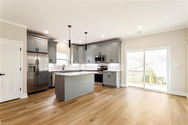 kitchen featuring gray cabinets, a kitchen island, appliances with stainless steel finishes, sink, and hanging light fixtures