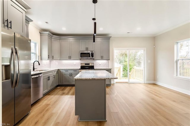 kitchen featuring gray cabinets, a kitchen island, decorative light fixtures, decorative backsplash, and stainless steel appliances