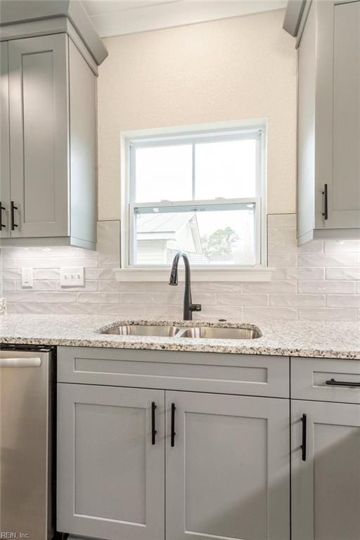 kitchen with gray cabinetry, sink, backsplash, and stainless steel dishwasher