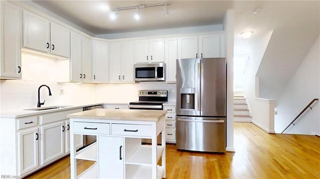 kitchen featuring sink, light wood-type flooring, white cabinets, and appliances with stainless steel finishes