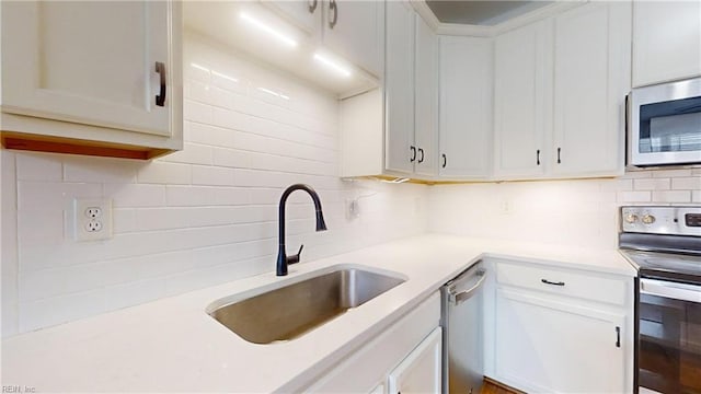 kitchen featuring appliances with stainless steel finishes, sink, decorative backsplash, and white cabinets