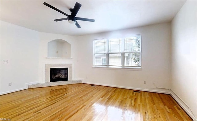 unfurnished living room featuring a tile fireplace, hardwood / wood-style floors, and ceiling fan