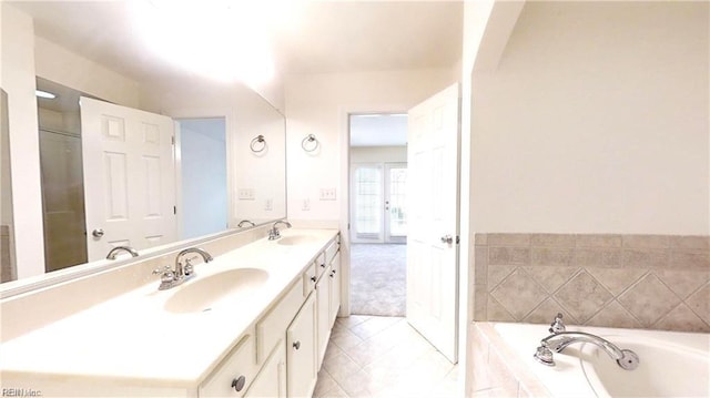 bathroom featuring tiled tub and vanity