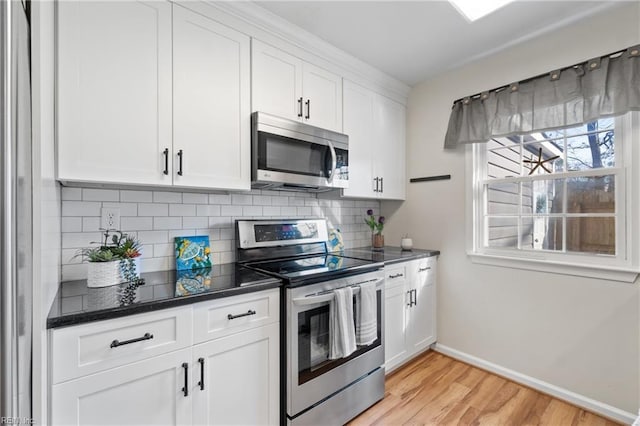 kitchen featuring white cabinetry, appliances with stainless steel finishes, light hardwood / wood-style floors, and decorative backsplash