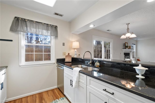 kitchen featuring a wealth of natural light, sink, white cabinets, dark stone counters, and stainless steel dishwasher