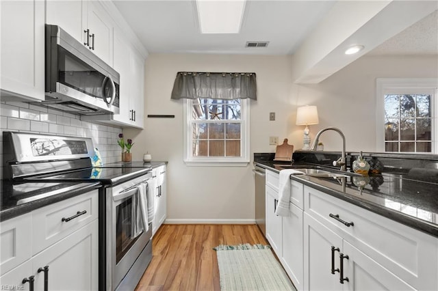 kitchen with white cabinetry, decorative backsplash, stainless steel appliances, and dark stone countertops