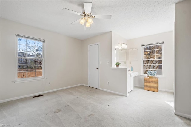 carpeted empty room featuring ceiling fan and a textured ceiling