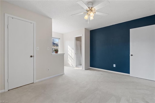 unfurnished room featuring ceiling fan, light colored carpet, and a textured ceiling