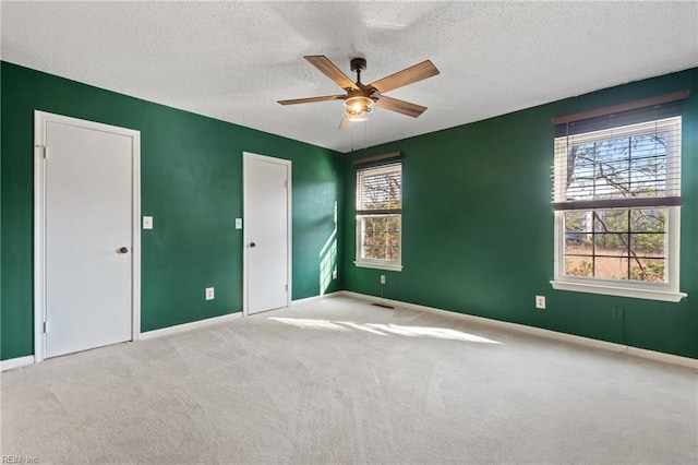 spare room featuring a textured ceiling, light colored carpet, and ceiling fan