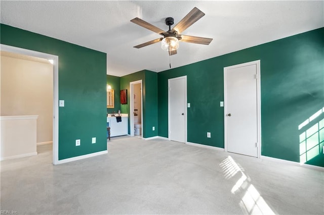 unfurnished bedroom with connected bathroom, light colored carpet, and ceiling fan