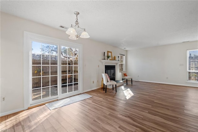 unfurnished room featuring wood-type flooring, plenty of natural light, a textured ceiling, and an inviting chandelier