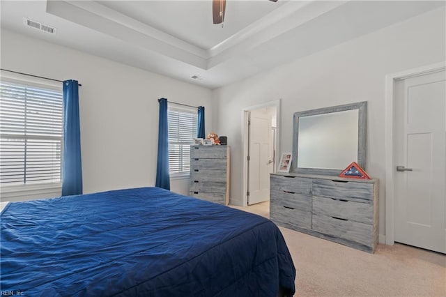 carpeted bedroom featuring ceiling fan and a tray ceiling