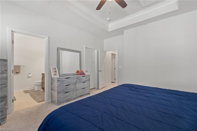 carpeted bedroom featuring ceiling fan, ensuite bath, and a tray ceiling