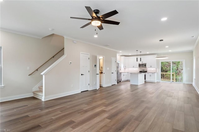 unfurnished living room with hardwood / wood-style floors, ornamental molding, and ceiling fan