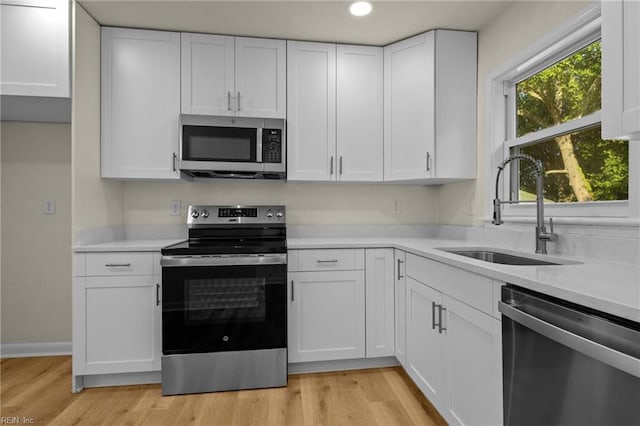 kitchen with white cabinetry, appliances with stainless steel finishes, sink, and light hardwood / wood-style flooring