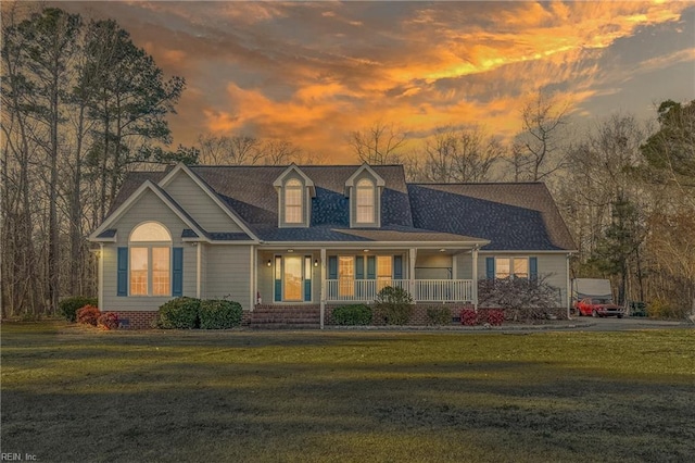 cape cod home featuring a yard and covered porch