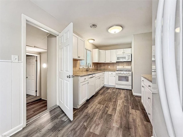 kitchen with white cabinetry, white appliances, light stone countertops, and dark wood-type flooring