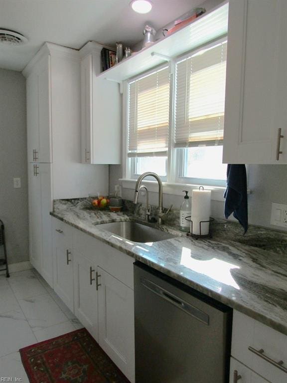 kitchen with white cabinetry, sink, light stone counters, and stainless steel dishwasher