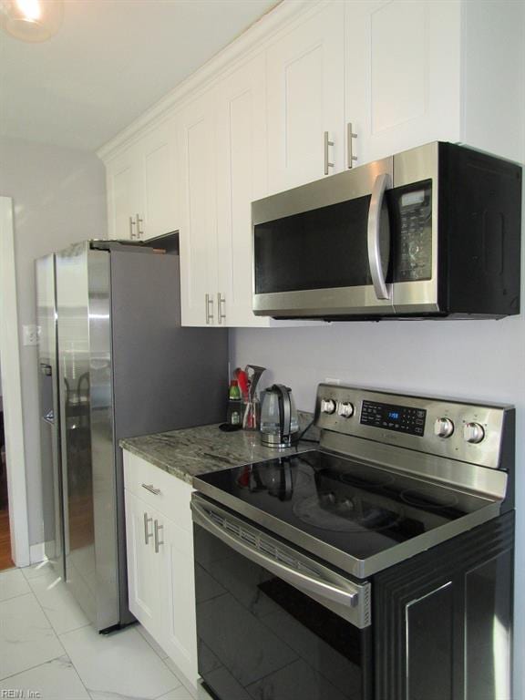 kitchen featuring white cabinetry, stainless steel appliances, and light stone counters