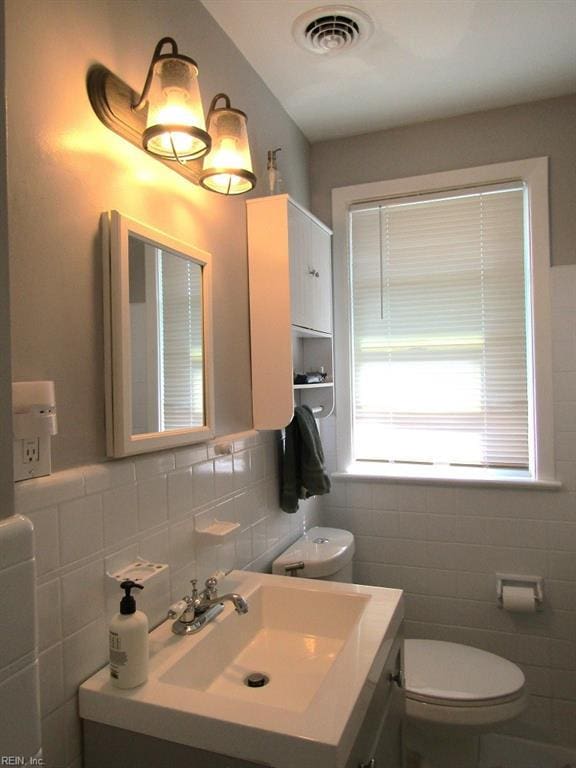 bathroom with vanity, toilet, and tile walls