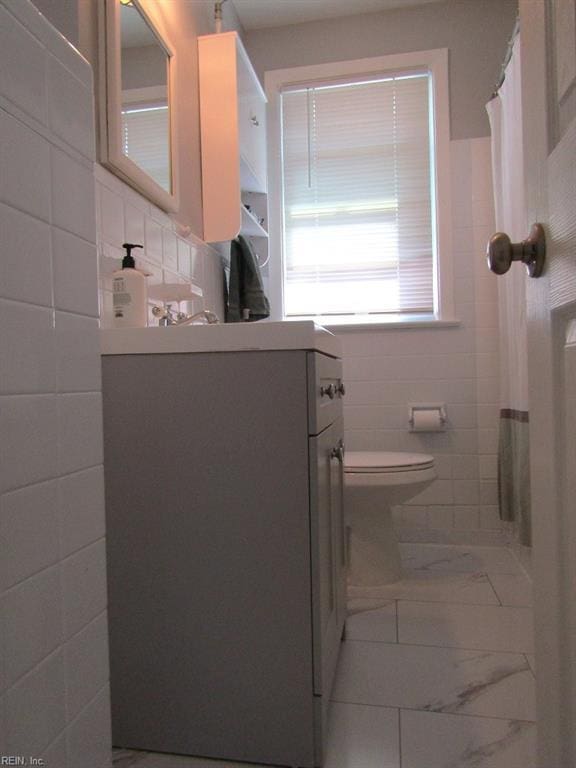 bathroom with vanity, toilet, and tile walls