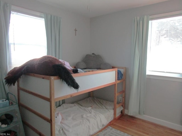 bedroom with multiple windows and hardwood / wood-style flooring