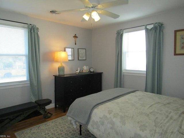 bedroom with hardwood / wood-style flooring, ceiling fan, and multiple windows