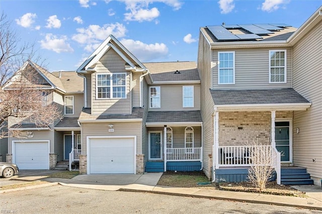 view of front facade with a porch, a garage, and solar panels