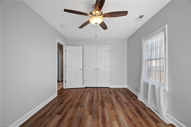 unfurnished bedroom featuring ceiling fan, dark hardwood / wood-style floors, and a closet