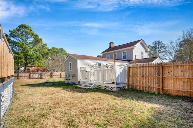 rear view of house with a wooden deck and a lawn