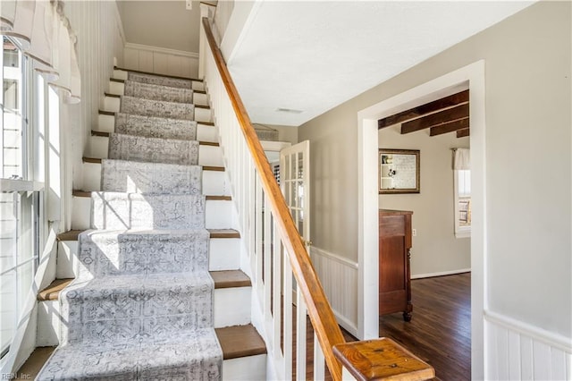 stairs featuring wood-type flooring and beamed ceiling