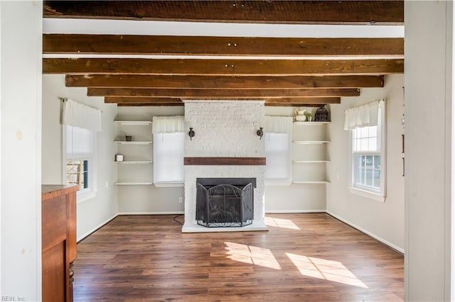 unfurnished living room featuring beamed ceiling, a large fireplace, and hardwood / wood-style flooring