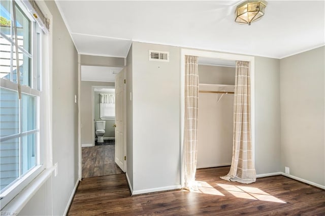 unfurnished bedroom with crown molding, dark hardwood / wood-style floors, and a closet