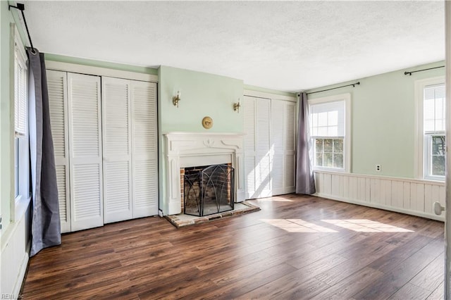 unfurnished living room featuring plenty of natural light, dark hardwood / wood-style floors, and a textured ceiling