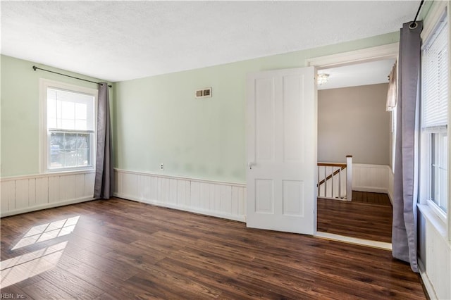 empty room with a textured ceiling and dark hardwood / wood-style flooring