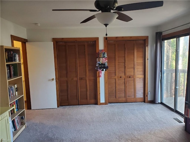 unfurnished bedroom featuring multiple closets, ceiling fan, light carpet, and access to outside