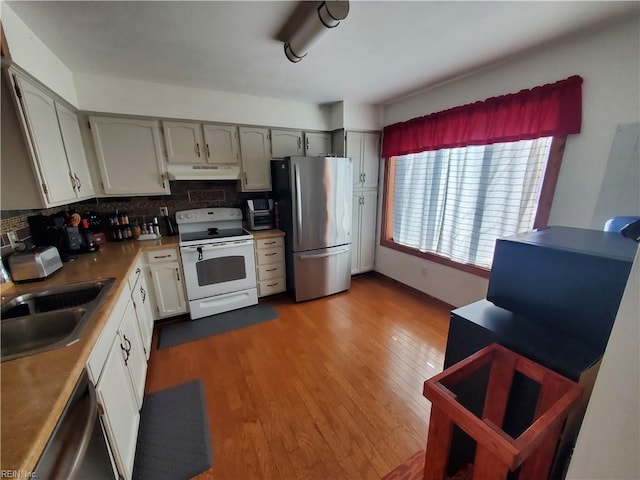 kitchen featuring sink, gray cabinets, stainless steel appliances, tasteful backsplash, and light hardwood / wood-style floors