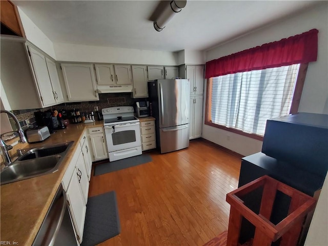 kitchen featuring appliances with stainless steel finishes, sink, backsplash, and light hardwood / wood-style floors