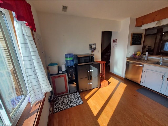 kitchen with white cabinetry, sink, stainless steel appliances, and light hardwood / wood-style floors