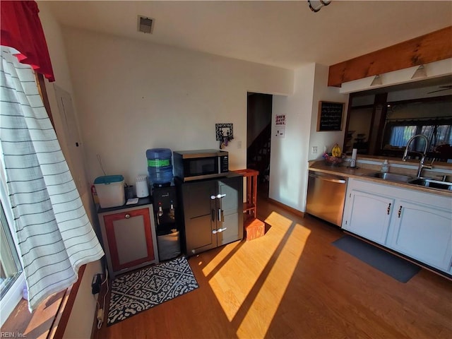 kitchen featuring sink, light hardwood / wood-style flooring, stainless steel counters, appliances with stainless steel finishes, and white cabinetry