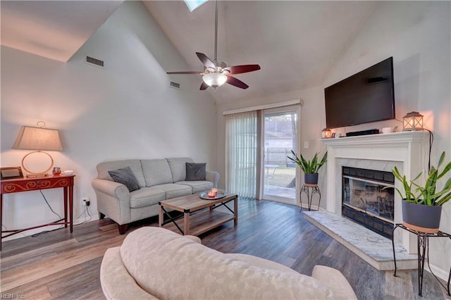 living room featuring hardwood / wood-style flooring, ceiling fan, a premium fireplace, and high vaulted ceiling