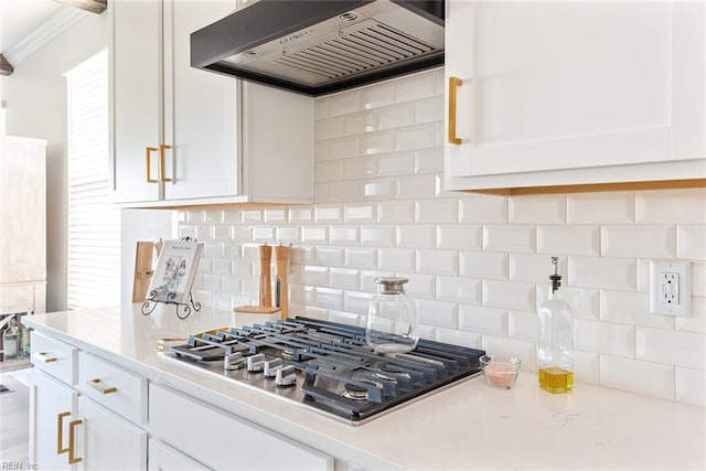 kitchen featuring white cabinetry, tasteful backsplash, ornamental molding, stainless steel gas cooktop, and wall chimney exhaust hood