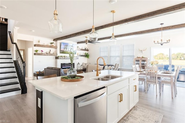 kitchen with decorative light fixtures, white cabinetry, sink, stainless steel dishwasher, and a center island with sink